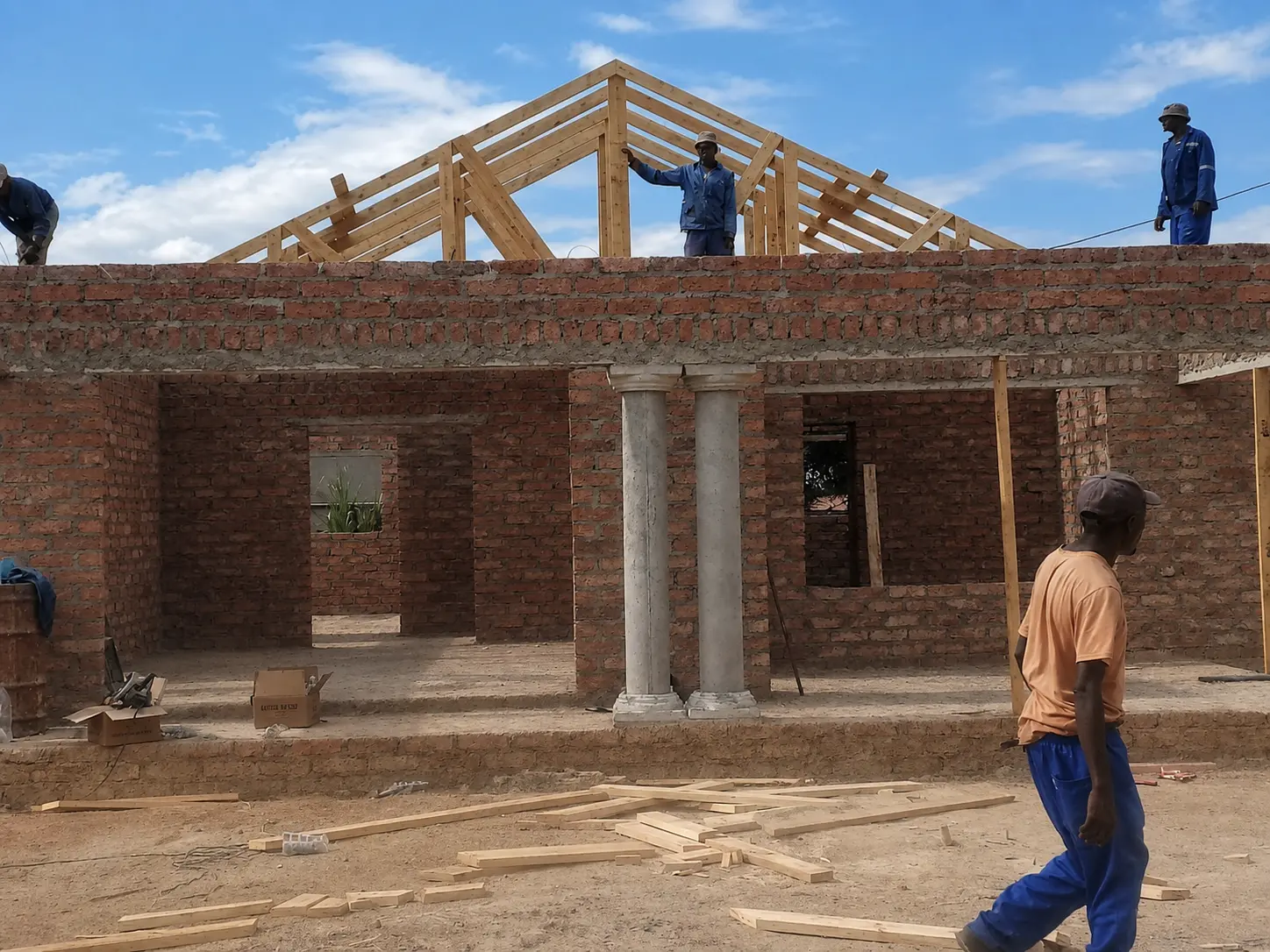 Team erecting timber roof trusses on a brick structure