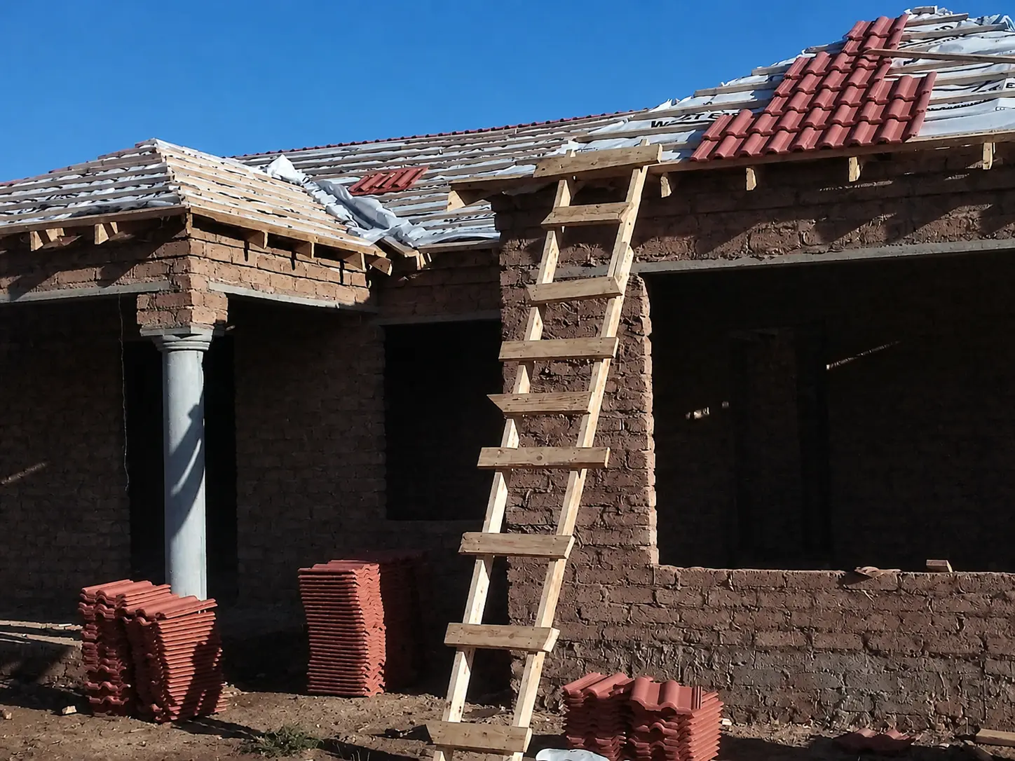 Roofer laying clay roof tiles on a new build