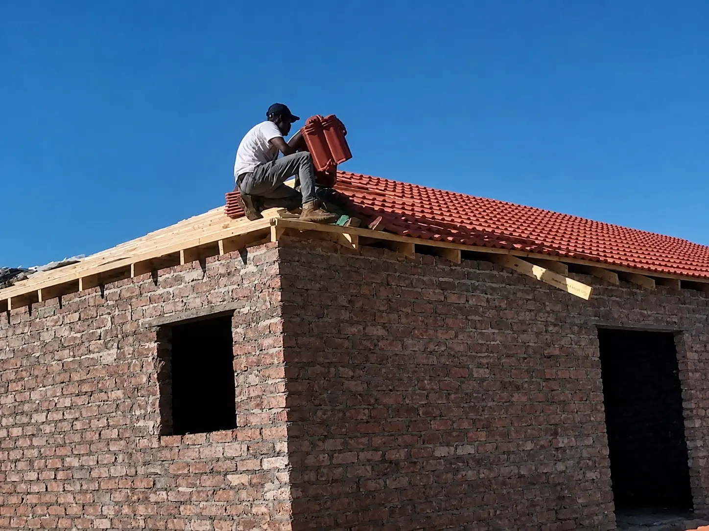 Roof tiling in progress with stacked tiles on site